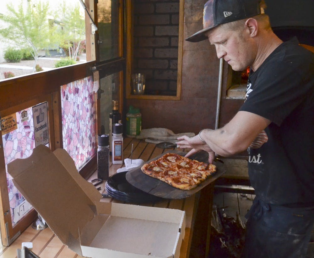 Louis Mentillo, one half owner operator of a-dough-be pizza prepares a pepperoni mushroom pizza to go on Wednesday evening at the Ridgeview Park. A-dough-be pizza is a 14 month old local business that specializes in homemade pizza using a wood burning oven in a mobile food truck. 
