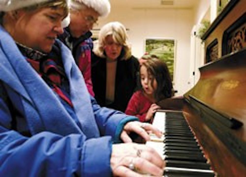 Krysten White, far right, sings a carol with, from left, Sally Fox, Bernadette See and Bettie Kaehele at President David Harris' house during the Hanging of the Greens on Friday. 