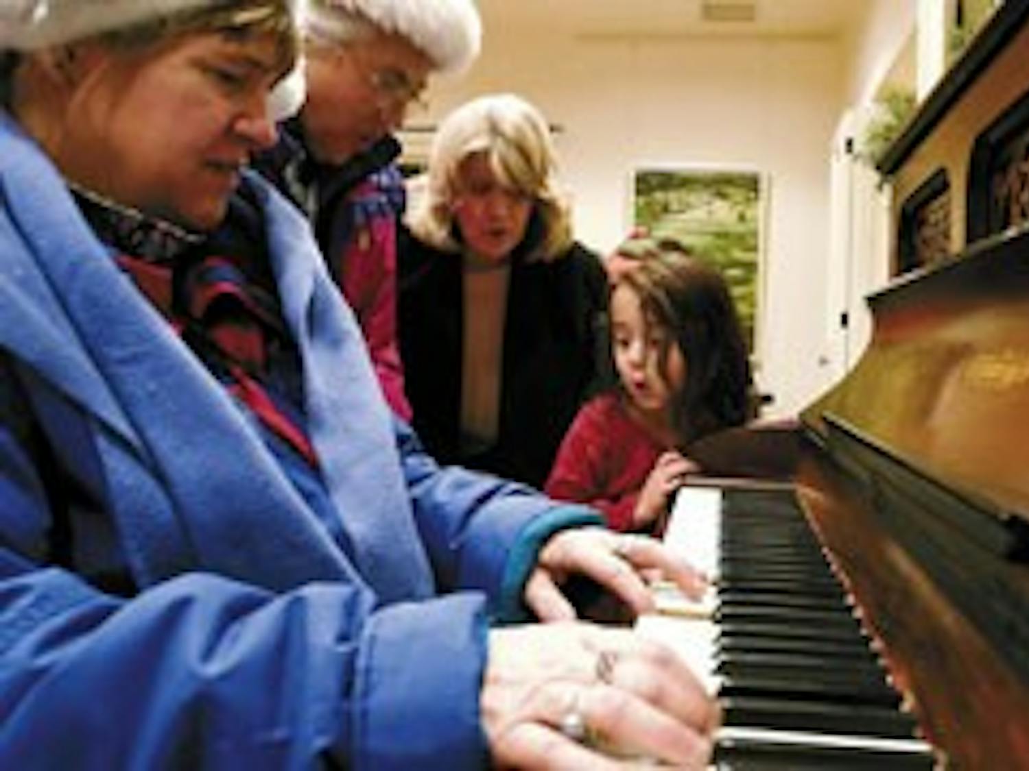 Krysten White, far right, sings a carol with, from left, Sally Fox, Bernadette See and Bettie Kaehele at President David Harris' house during the Hanging of the Greens on Friday.