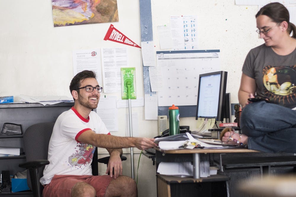 Newly selected editor-in-chief of the Daily Lobo, David Lynch, sits at his desk and speaks with outgoing Editor-in-Chief Jyllian Roach at a newsroom meeting Sunday afternoon in  Marron Hall. The Daily Lobo editor-in-chief position is held by a student for a one-year term.