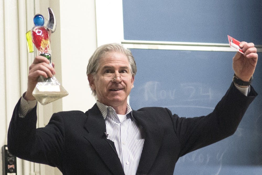 Former Enron CFO Andrew Fastow raises both his “CFO of the Year” award and prisoner identification card during his presentation at the Anthropology building on Monday. The presentation, titled “Rules versus Principles,” was put on by the Daniels Fund Ethics Initiative at UNM, which supports business ethics education.