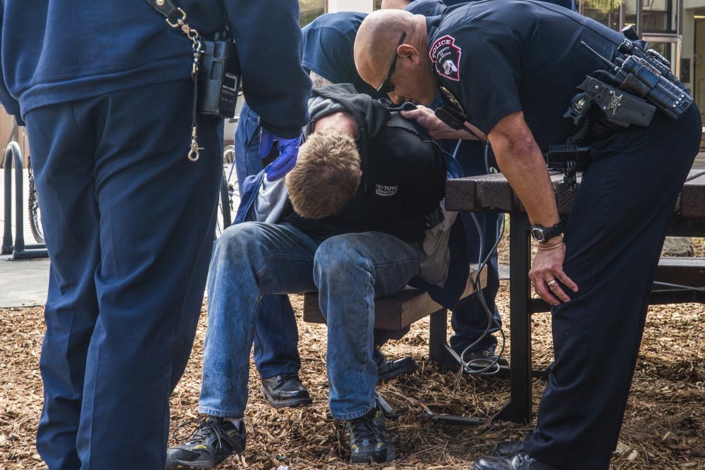 UNMPD officers handcuff a man near the Biology Department on Tuesday, April 19, 2016.