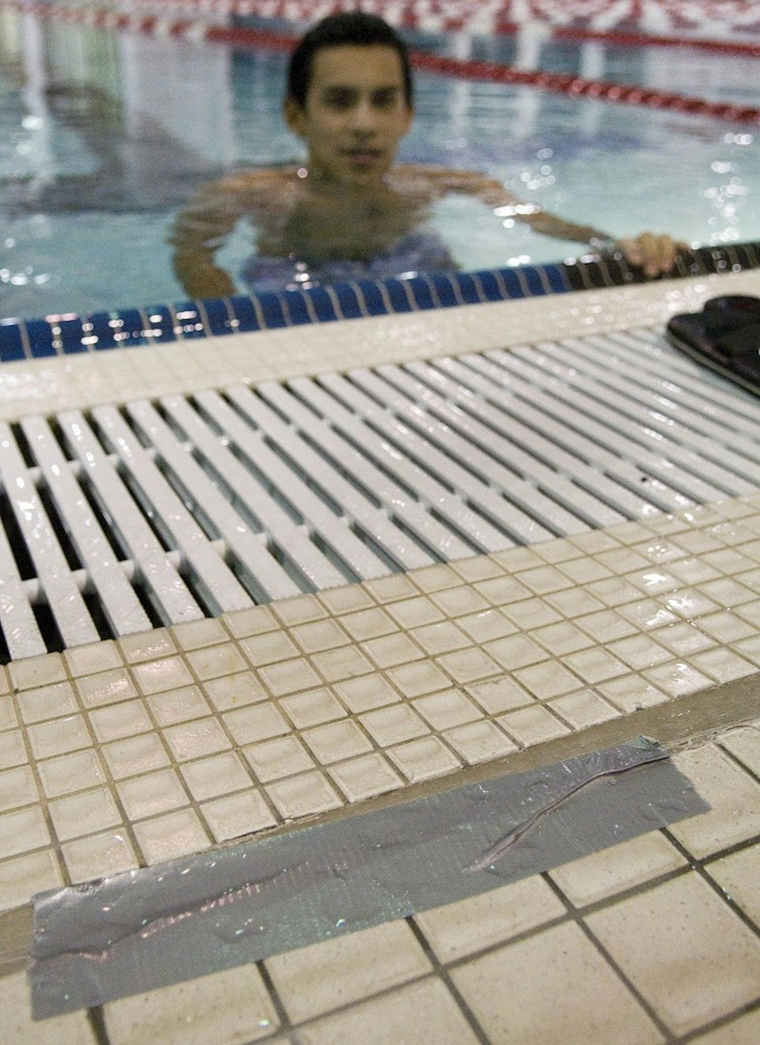 	Student Angelo Leon finishes a lap in front of duct-taped tiles in the Olympic Pool in Johnson Center on Wednesday. The tiles, which were installed during renovation of the pool in March, have already popped up out of the caulking and need to be repaired.