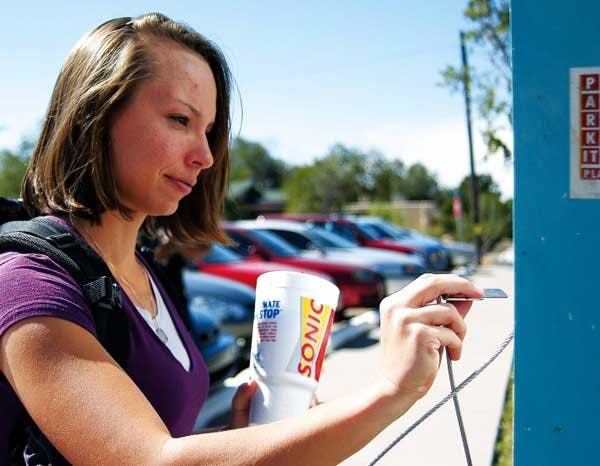 UNM student Tara Kraus pays for parking Tuesday at a lot on Gold Avenue and Buena Vista Drive. The lot is the proposed site for a four-story 51 condominium building. 