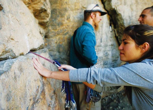 Student Nicole Telles practices setting a cam during a rock-climbing lesson in Tijeras Canyon on Sunday.