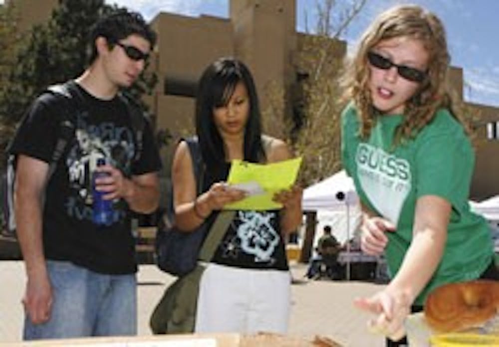 Students Adam Chavez, left, and Ellen Cruz, center, read pamphlets about sexual assault prevention passed out by student Caitlin Potter at a Student Health Center booth on Smith Plaza on Wednesday. Booths were set up on the plaza to promote National Sexua