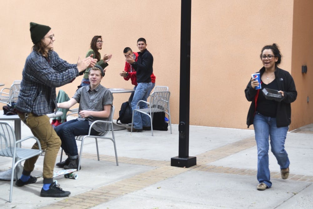 A group of UNM students clap when Maria Valdez, a senior Early Childhood Mutual Cultural Education major, walks out of the SUB on Tuesday. Students Christian Puckett, left, and Levi Martinez  started AntiSocial, a YouTube channel that records videos of themselves putting students in awkward situations.
