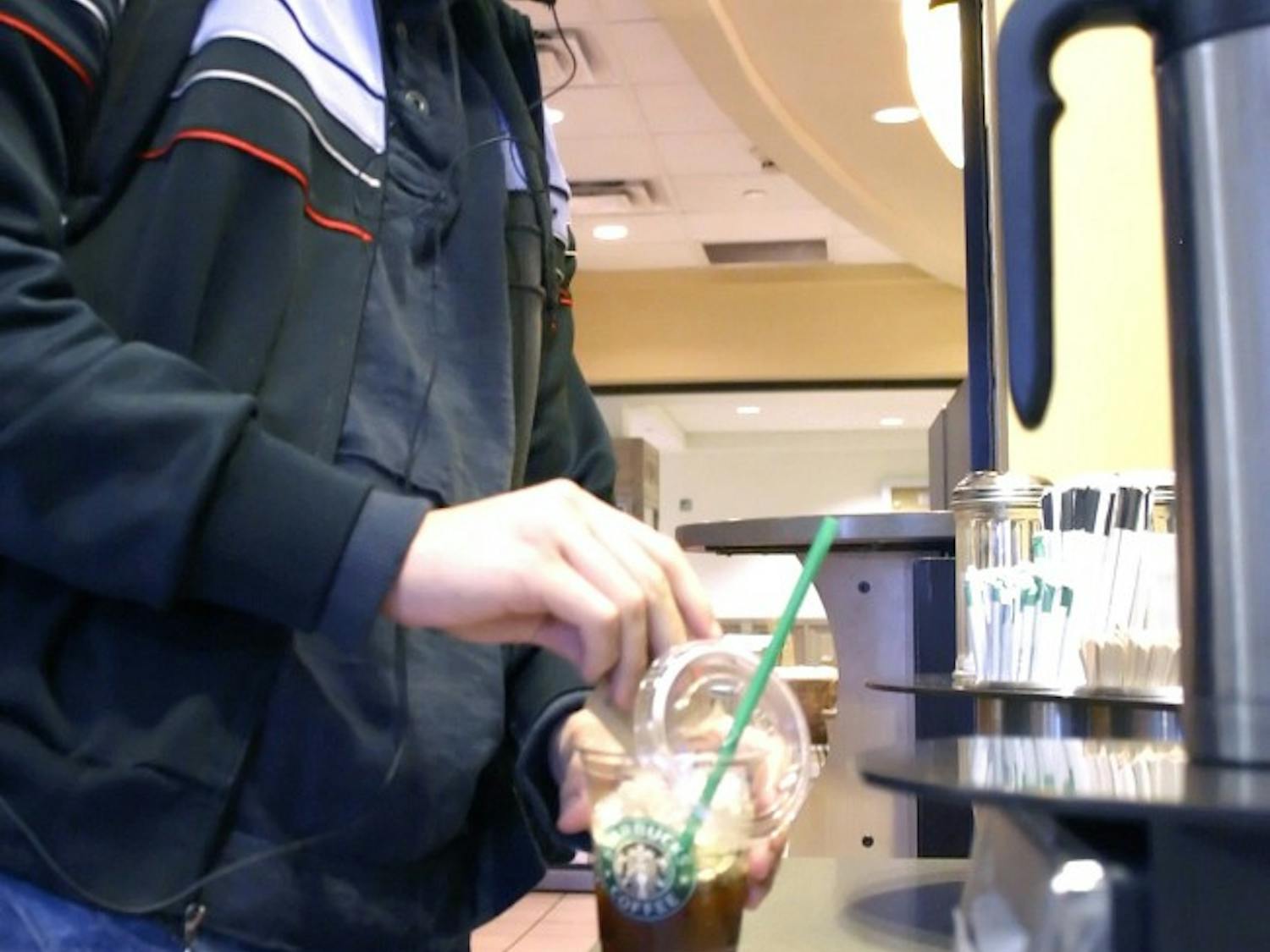 UNM student Julio Romero adds sugar to his iced espresso Tuesday outside of Starbucks at Zimmerman Library. Starbucks will open another coffee shop at Central Avenue and Terrace Street. It will be the fourth Starbucks within one mile of the University.