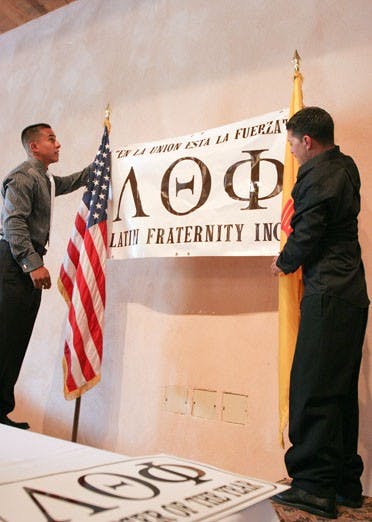Lambda Theta Phi fraternity members Peter Estrada, left, and Gian Chaves hang a banner for a July 25 banquet at the National Hispanic Cultural Center. 
