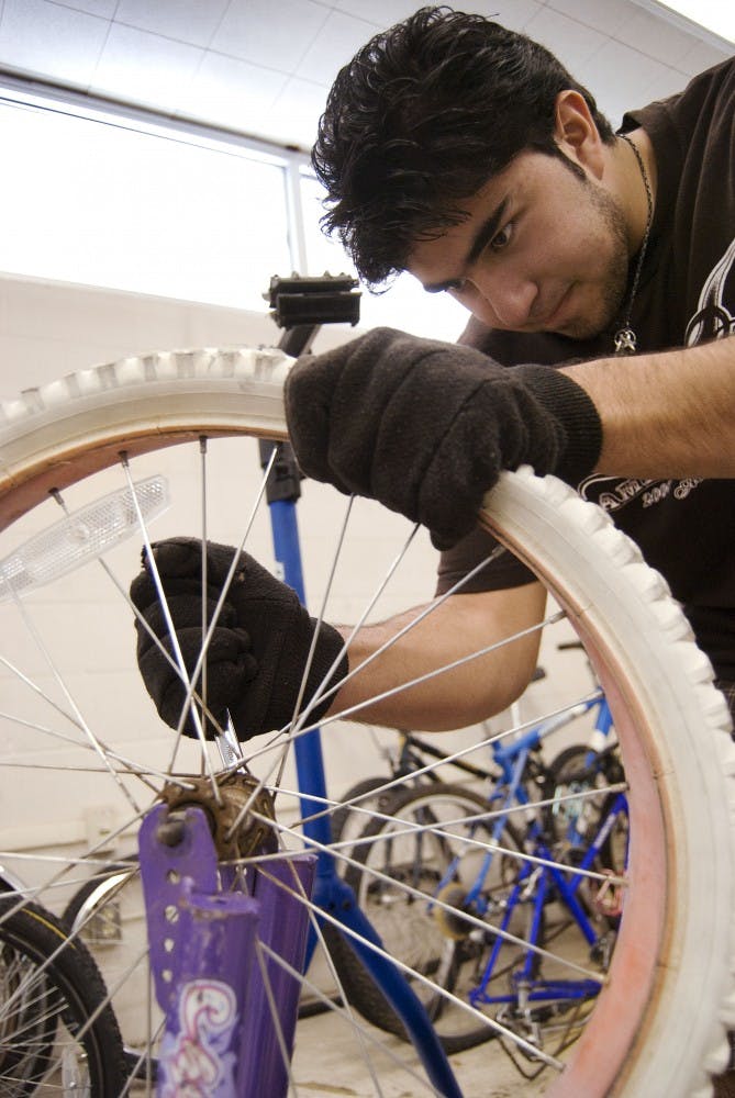 	Miko Serna, member of the Lambda Theta Phi Latin fraternity, tightens down a pink bicycle’s front wheel at Esperanza Branch Library Saturday. The fraternity spent four hours on Saturday fixing bicycles to be distributed to Albuquerque’s needy children. 