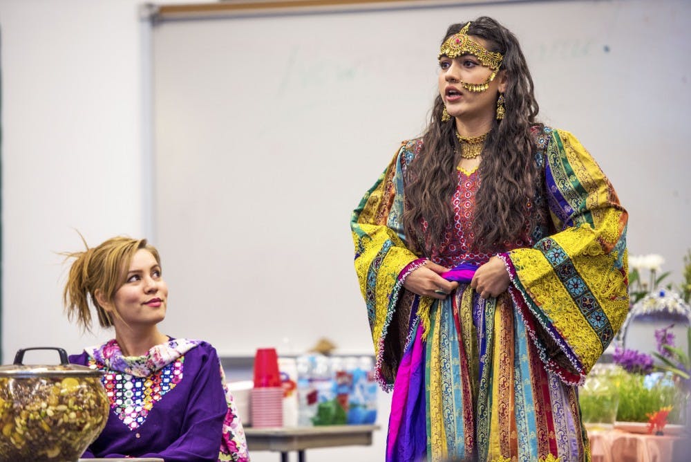 Ehlam Yosufzai, right, explains facets of the Afghani New Year known as Nowruz during a Refugee Well-being Project gathering at the Cesar Chavez Community Center on Tuesday, March 21, 2017. The project sets students on a two-semester course during which they help refugee families and have the opportunity to learn about various cultures.