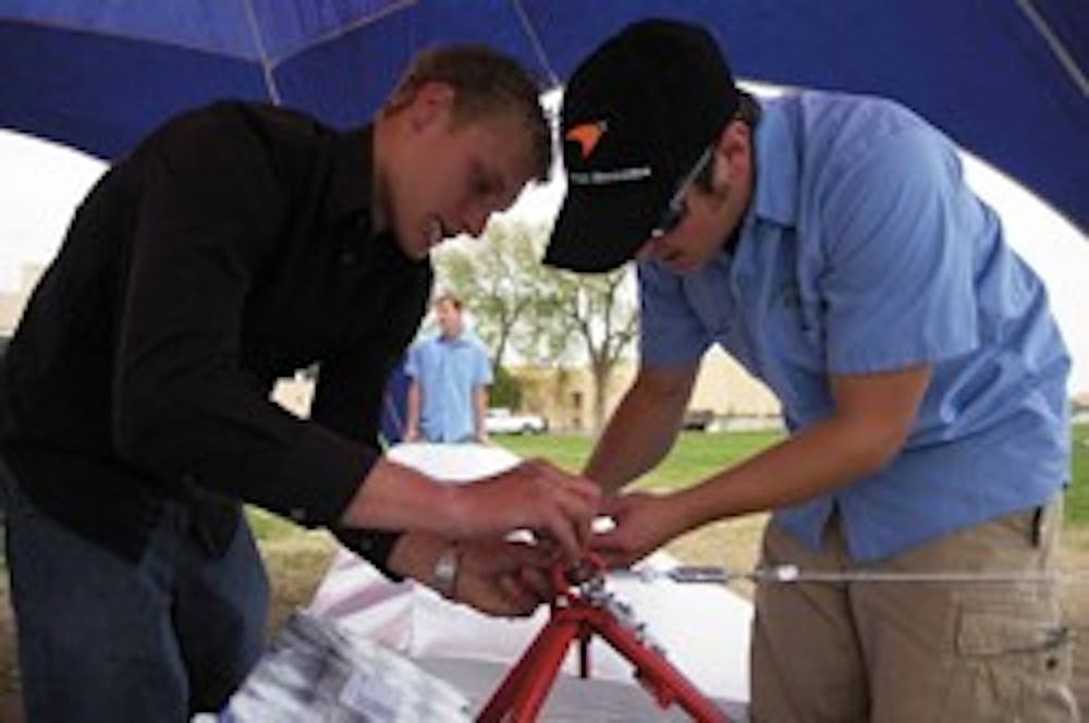 Chris Keaty, left, and pilot Austin Wetsch, team members of El Vuelo Del Lobo, work on their Flugtag glider during Fiestas on Saturday at Johnson Field.