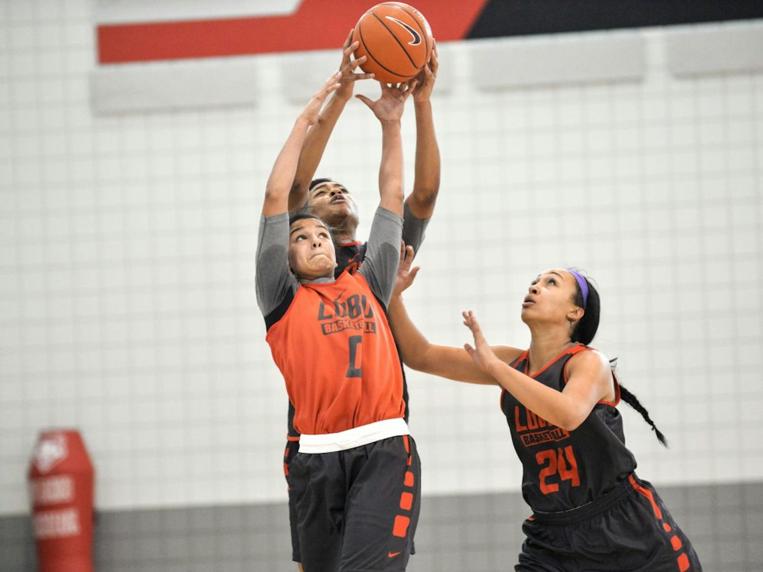 Cherise Beynon (0) reaches past Khadijah Shumpert and Jayda Bovero (24) during their second practice of the season on Oct. 6 at the Davalos Training Center. The Lobo Howl event will be held at WisePies Arena this Friday at 6 p.m..