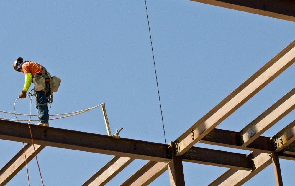 	A construction worker stands from a beam as part of the phase-two addition to Castetter Hall. The new biology wing is one of several new projects on main campus.