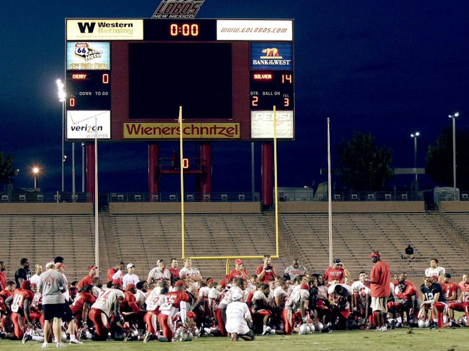 Head coach Mike Locksley and his team gather at midfield after a recent practice. The Lobos will head to College Station, Texas, to face Texas A&M on Saturday.