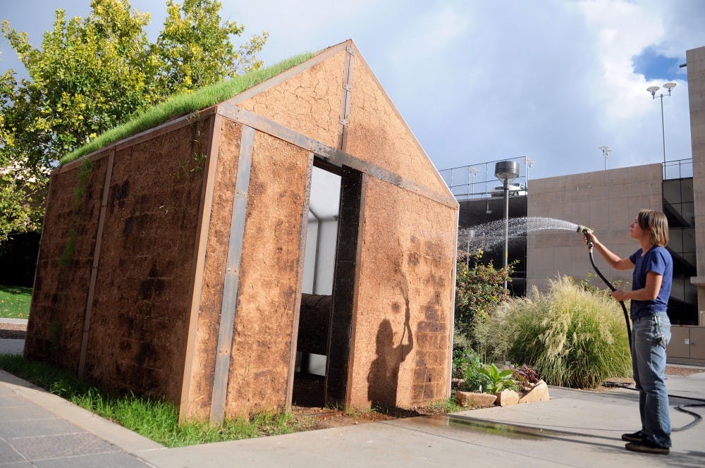 	Nina Dubois waters her project “Cultural Digest(e)” in front of Johnson Gym on Monday. Compost from the UNM community is used to maintain the earth house. 