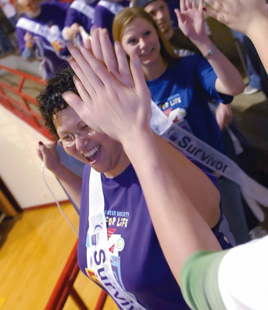 Cancer survivor Marea De Leon high-fives participants in the Relay for Life charity walk in Johnson Gym on Friday. More than 200 people participated in the event sponsored by American Cancer Society's Colleges Against Cancer program. About $12,000 was rai