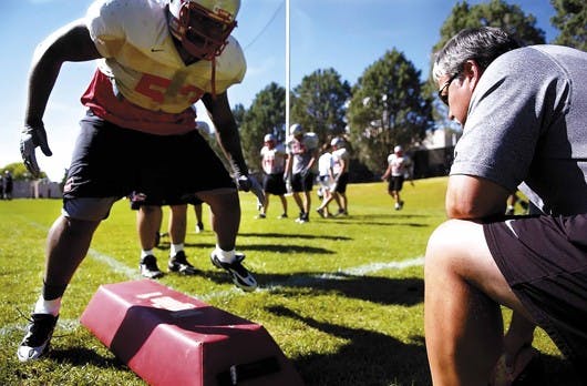 Defensive end Kendall Briscoe runs a conditioning drill with defensive end coach Lenny Rodriguez on Thursday at the UNM football practice field. 