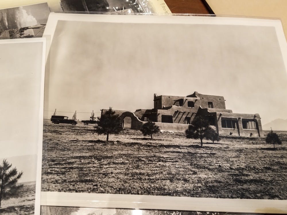 Photos at the University Archives are splayed across a table. The images were taken in 1930, just after the completion of the UNM president’s house on campus.