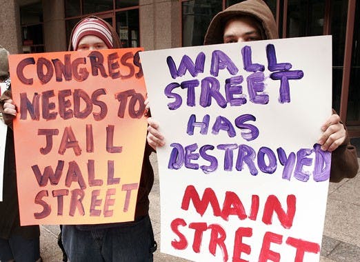 Students Alex Clay, left, and Raymond Kadane hold signs in front of Tom Udall's Downtown office on Friday. Protesters gathered to complain about federal bailout money being used to fund bonuses for corporate executives.
