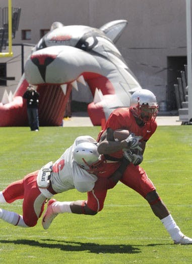 Wide receiver Roland Bruno wriggles free of cornerback Anthony Hooks' grasp during Saturday's annual Cherry-Silver scrimmage at University Stadium. Silver defeated Cherry 24-21 on a last-minute field goal.