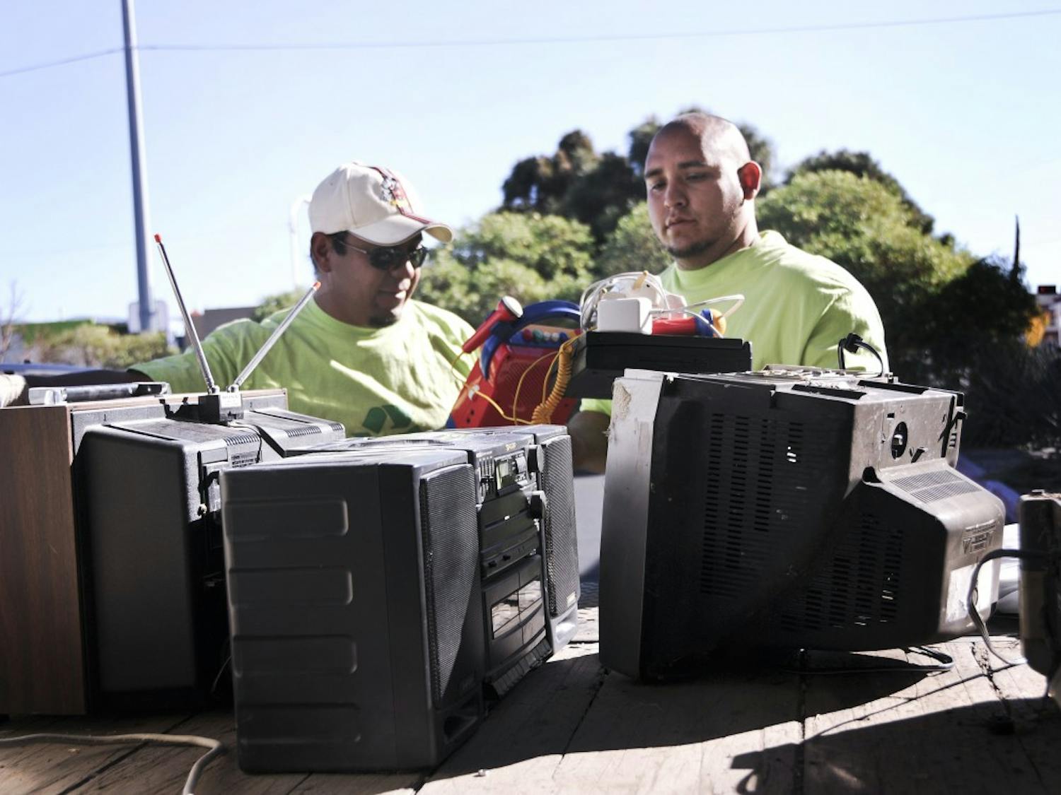 	Jesus Ramirez, left, and Andres Lopez load old TVs and stereos to be recycled in A lot on Saturday. The student group Net Impact is collecting electronic waste for recycling. 