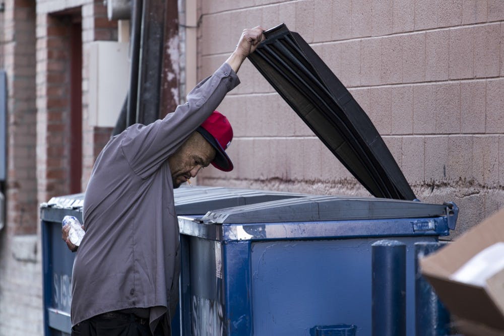 An Albuquerque homeless man looks through a trash can on Central Avenue on the evening of Jan. 17, 2018.