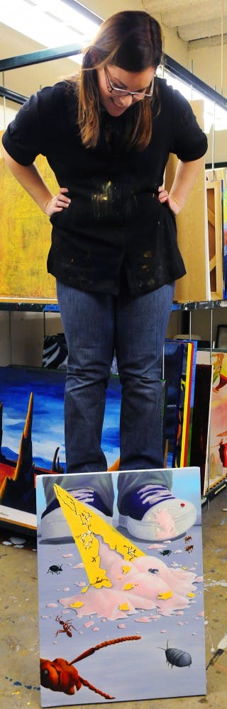 	Student Katie Carillo looks at her painting, titled “Calling all Crawlers,” in the Art Building on Wednesday. Carillo was working on her final project for her first painting class.