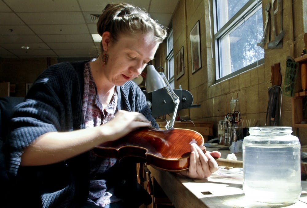 	Cedra Wood varnishes a violin at the violin shop. Cedra is a graduate student who won an violin making award.