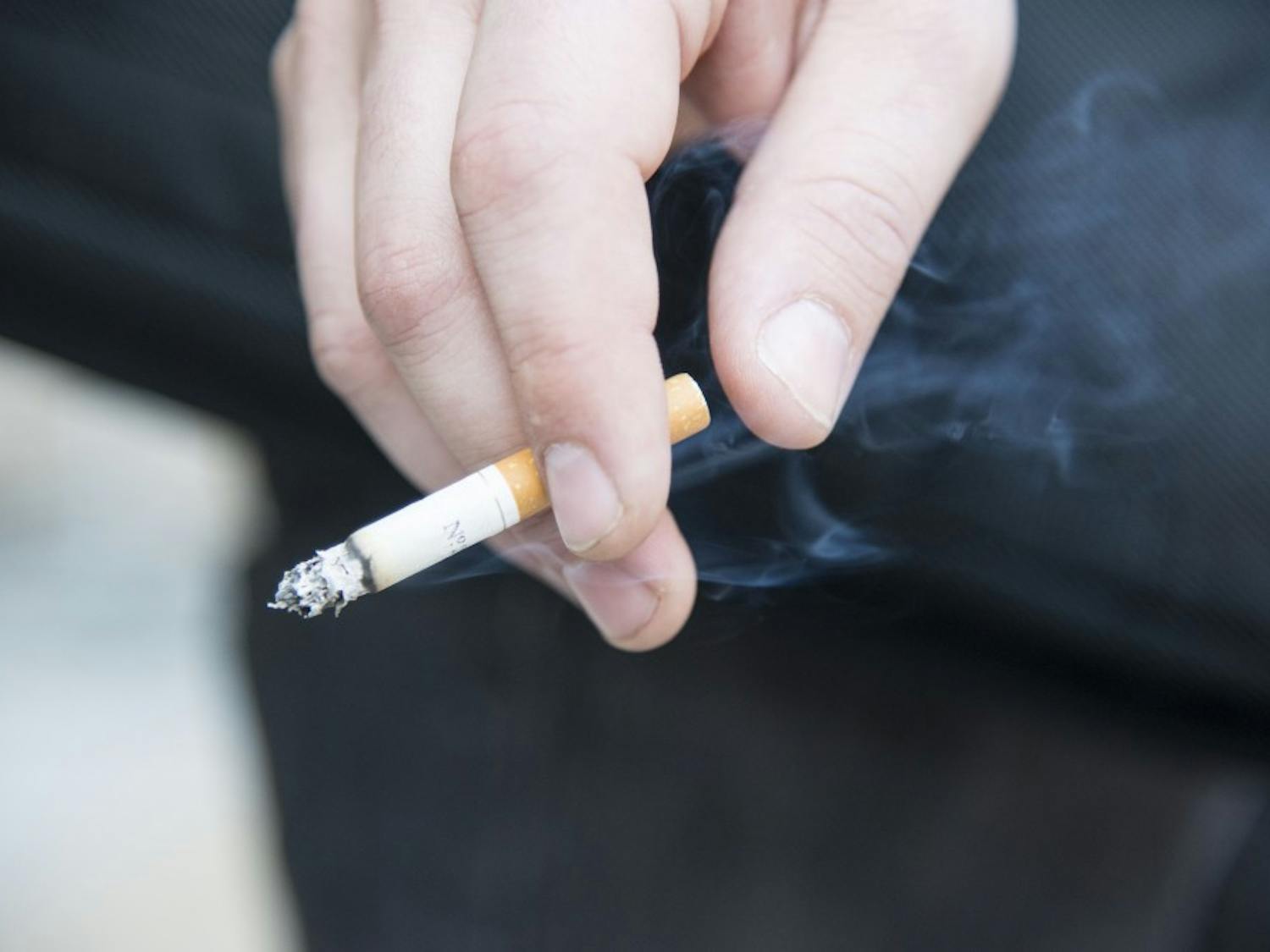 A student smokes outside Castetter Hall on Tuesday afternoon. UNM is considering a revision to the universitys smoking policy to include cracking down on smokers outside of designated smoking areas on campus.