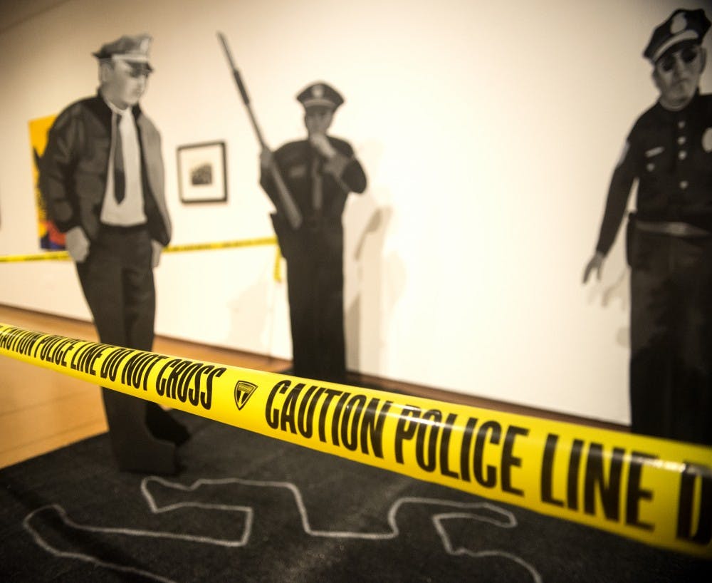 An instillation of police officers around a chalk outline stands at the Necessary Force: Art in the Police State exhibit at the Popejoy Museum. The exhibit hosts art pieces that range from an interactive police baton/microphone to a full size police interceptor flipped on its roof. 