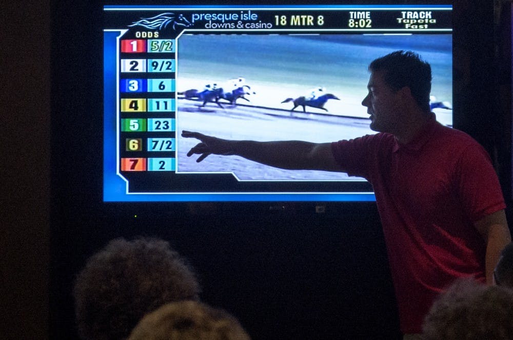 Adam Bubb points out the odds of a horse simulcast race during his class field trip to The Downs Racetrack &amp; Casino on Tuesday. Bubb encourages his students to think about gambling as a form of entertainment and not as a way to make money.