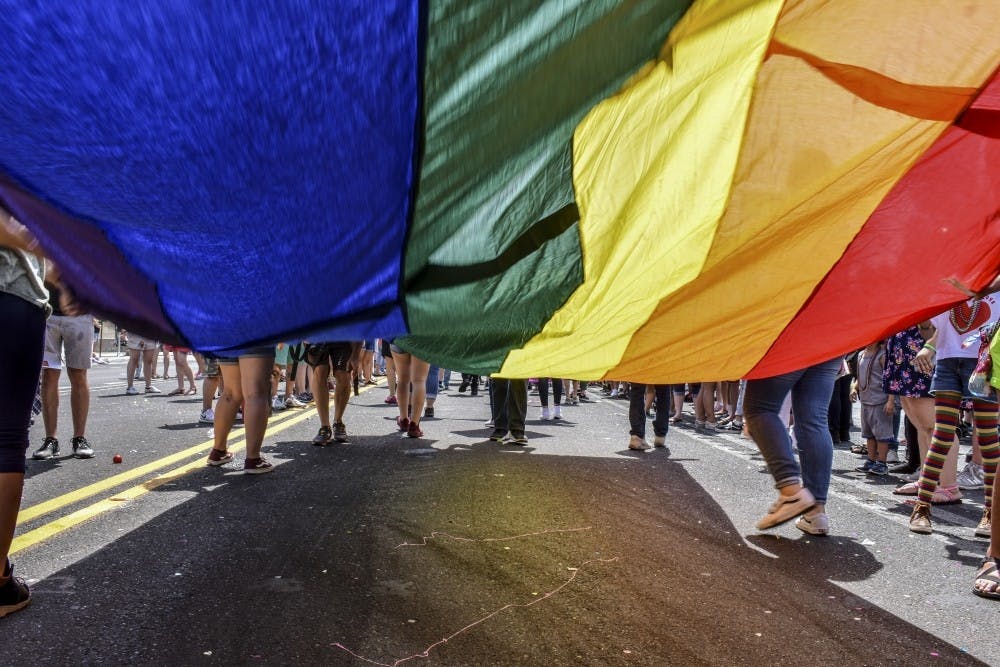 Pride participants carry a rainbow flag on Central Avenue during the 2018&nbsp;Albuquerque Pride Parade.