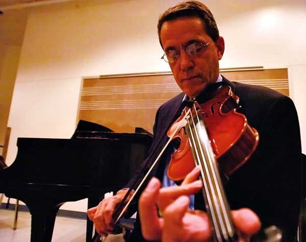 Dean of University College Peter White warms up before teaching a violin class Thursday in the Center for the Arts. White will resign from his administrative position after this semester. 