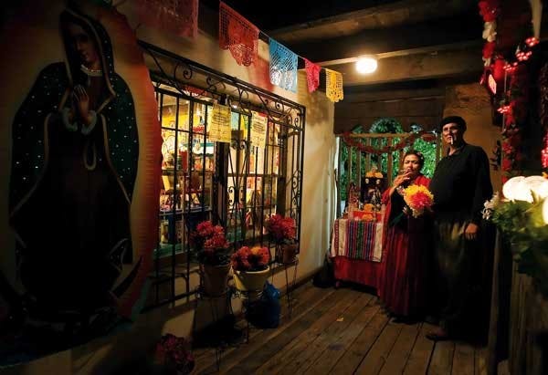 Lorraine Cardova-Carriaga and Ad&aacute;n Carriaga, dressed as Frida Kahlo and Diego Rivera, stand next to an altar on an Old Town patio during a Dia de los Muertos party Saturday.