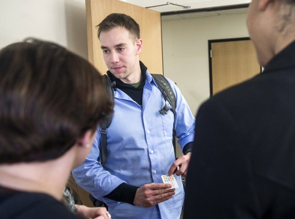 	Travis Kellerman, CEO and co-founder of Bandojo, hands out his business card to attendees of the Collegiate Entrepreneurs’ organization club on Thursday. UNM CEO is a new student organization
that aims to build connections between entrepreneurs and innovators across campus.