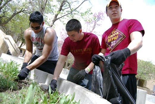 Sean Kesani, left, Matt Callahan, center, and Josh Padilla weed a planter near Student Family Housing on Saturday as part of Spring Storm. The event called for students to clean up areas on and near campus, and participants were rewarded with a concert an