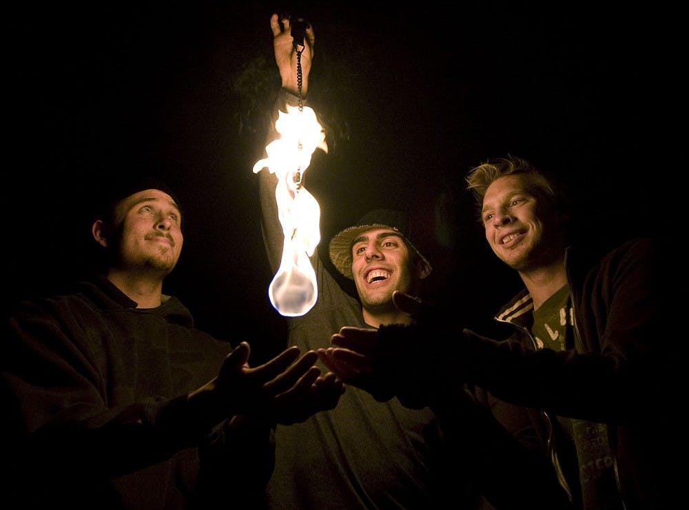 	Stuart Knight-Williamson, left, Pierce Knauber-Ferriegel, center, and Tyler Chapman warm their hands over a fireball Monday. They formed Ignite Poi about six months ago.