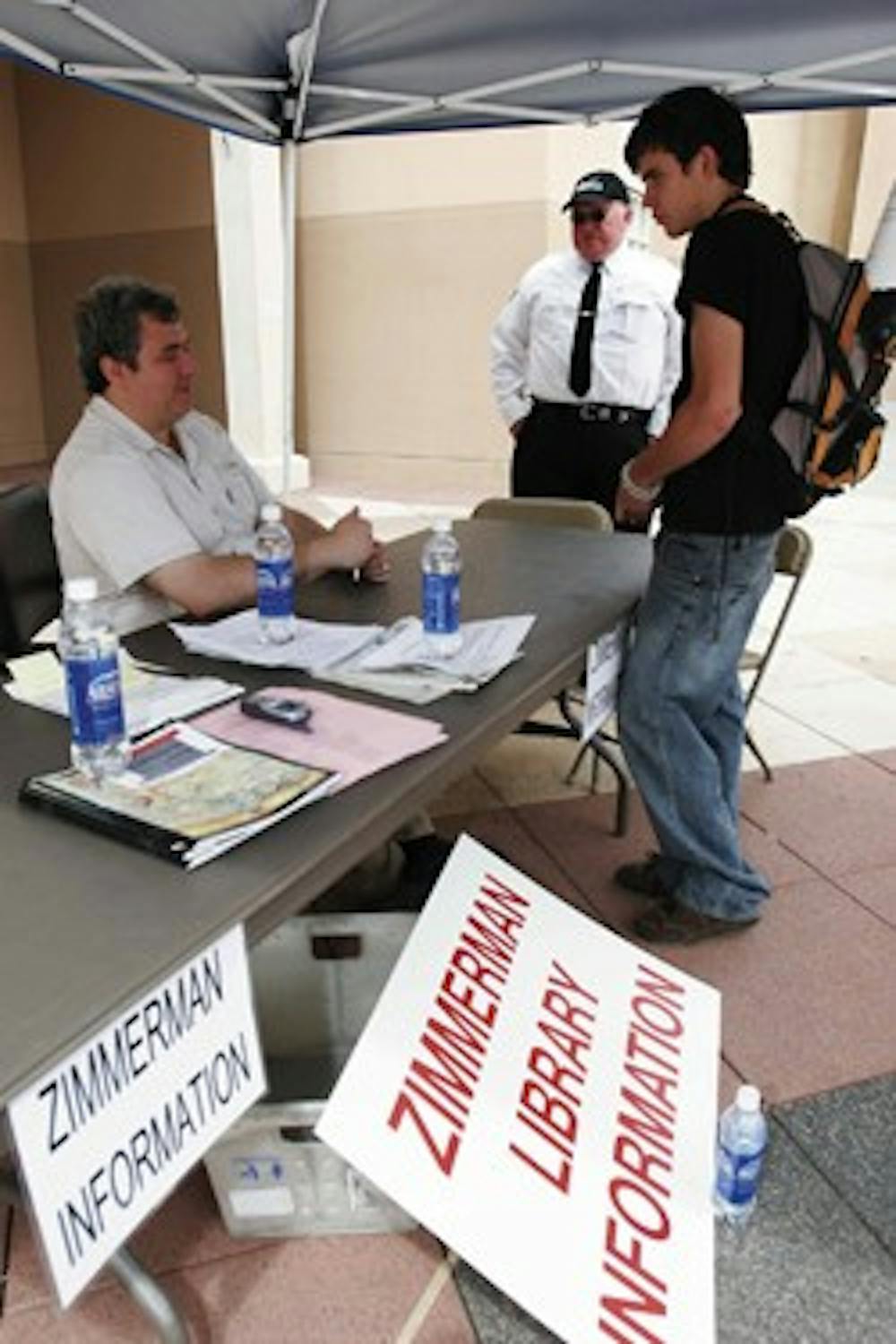 Freshman Neil Werbelow, right, asks Library Information Specialist Chris Johnson when books will be available to check out from Zimmerman Library. John Gill with Santa Fe Protective Services stands in the back.