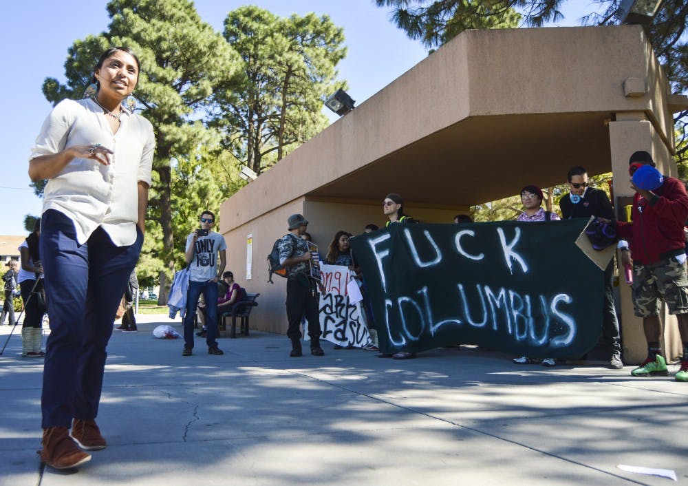 UNM fifth-year sociology/native science double major Keioshiah Peter speaks to protesters and other UNM students during a rally against Columbus Day at the G Lot shuttle stop on Monday afternoon. Protesters hung banners and eviction notices around that area, including the University House.