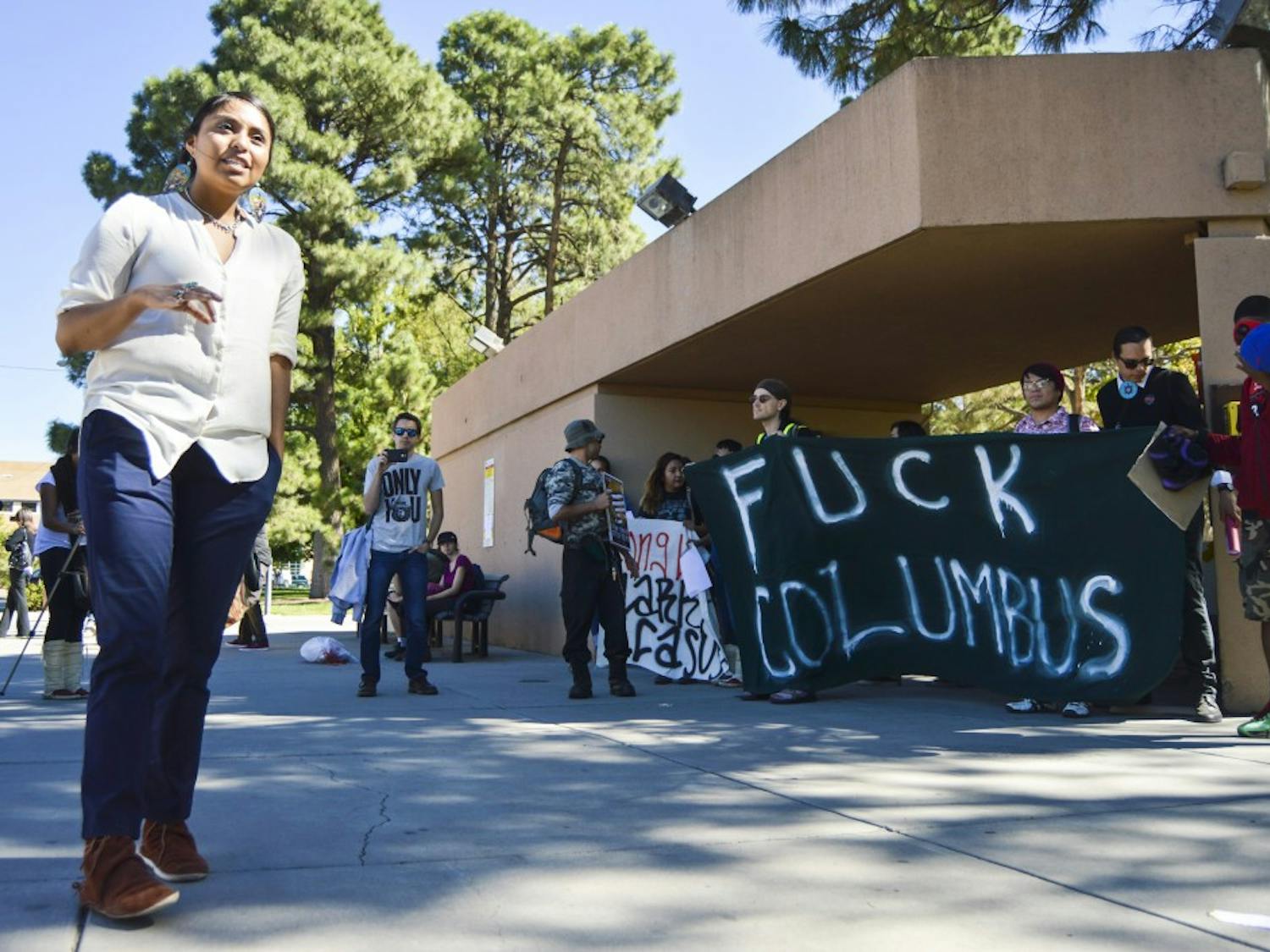 UNM fifth-year sociology/native science double major Keioshiah Peter speaks to protesters and other UNM students during a rally against Columbus Day at the G Lot shuttle stop on Monday afternoon. Protesters hung banners and eviction notices around that area, including the University House.