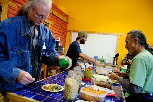 Leslie Feuerborn, left, serves himself sprouts during a meeting on the benefits of raw food Saturday.