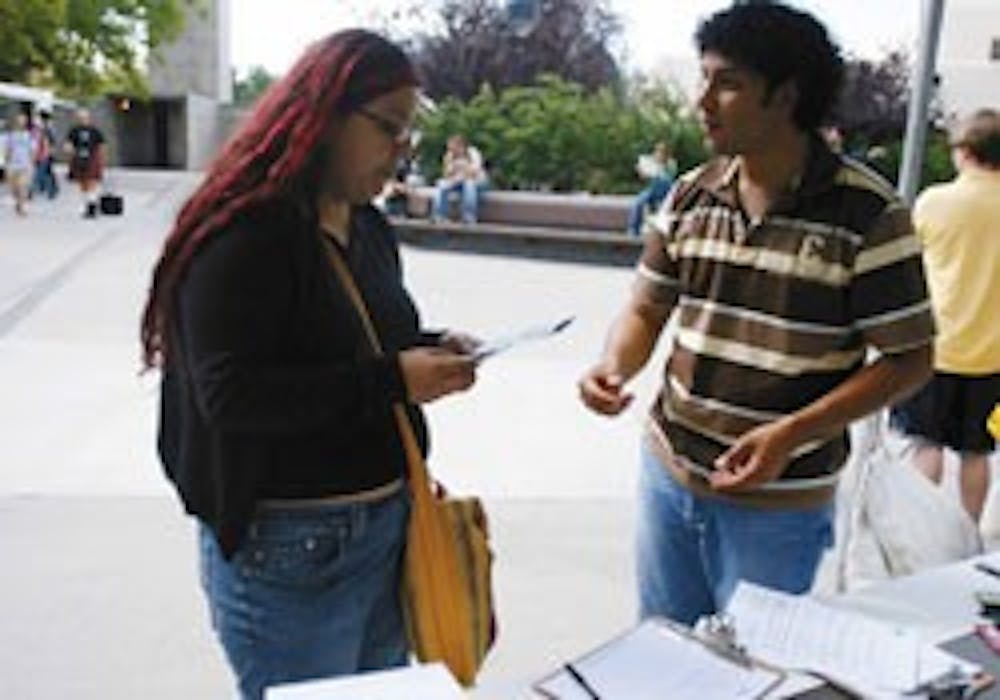 Martin Gutierrez, right, outreach coordinator for Communities United to Strengthen America, talks with Yvette Morales after she signed a petition at the Duck Pond on Friday. The petition was addressed to New Mexico Rep. Heather Wilson and asked for reduce