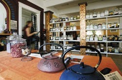 Charlotte Webster, owner of Summerhouse Tea and Trading Company, walks by tea-lined shelves in her store Saturday on Harvard Drive.