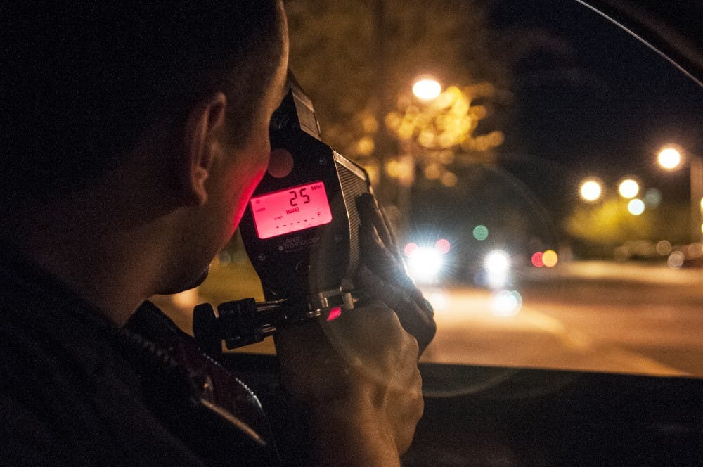 A UNMPD officer uses his radar gun to track how fast a car travels on UNM campus.&nbsp;