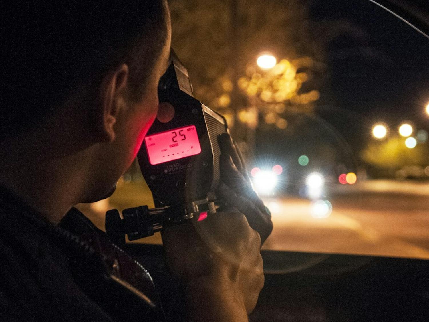 A UNMPD officer uses his radar gun to track how fast a car travels on UNM campus.&nbsp;
