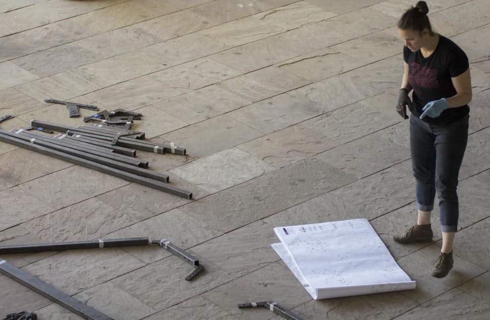 Rosa Castillo looks over blueprints for her teams playhouse project Tuesday at the School of Architecture and Planning. Castillo is surrounded by multiple frames that will be used by teams to construct their playhouses.  