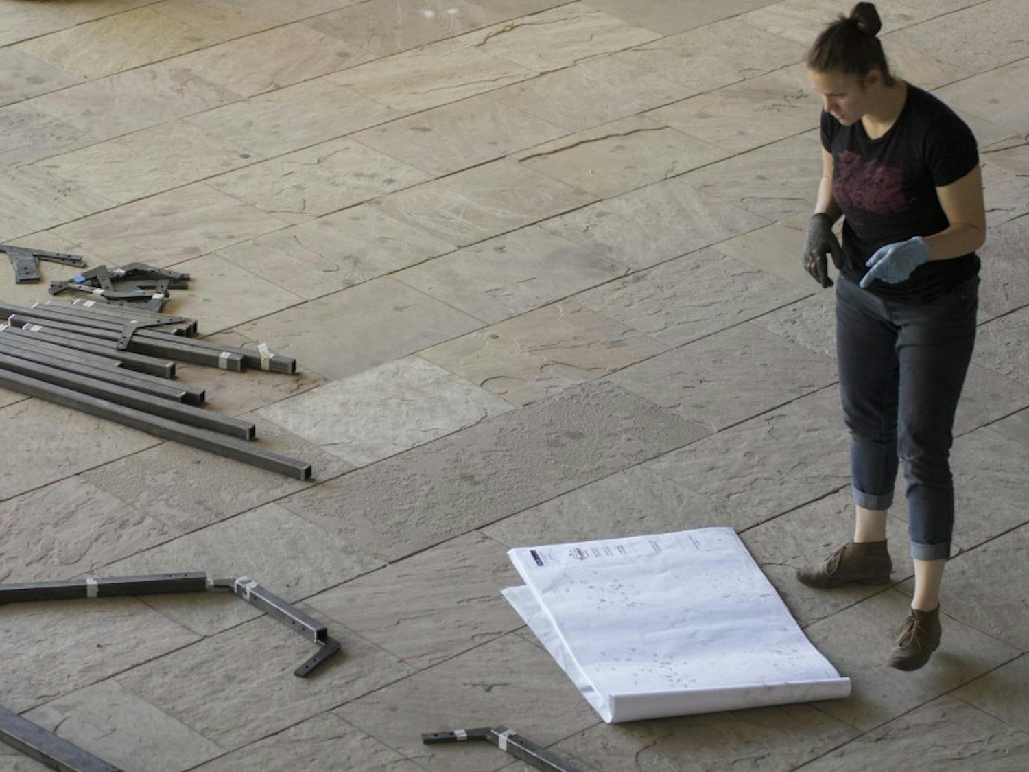 Rosa Castillo looks over blueprints for her teams playhouse project Tuesday at the School of Architecture and Planning. Castillo is surrounded by multiple frames that will be used by teams to construct their playhouses.