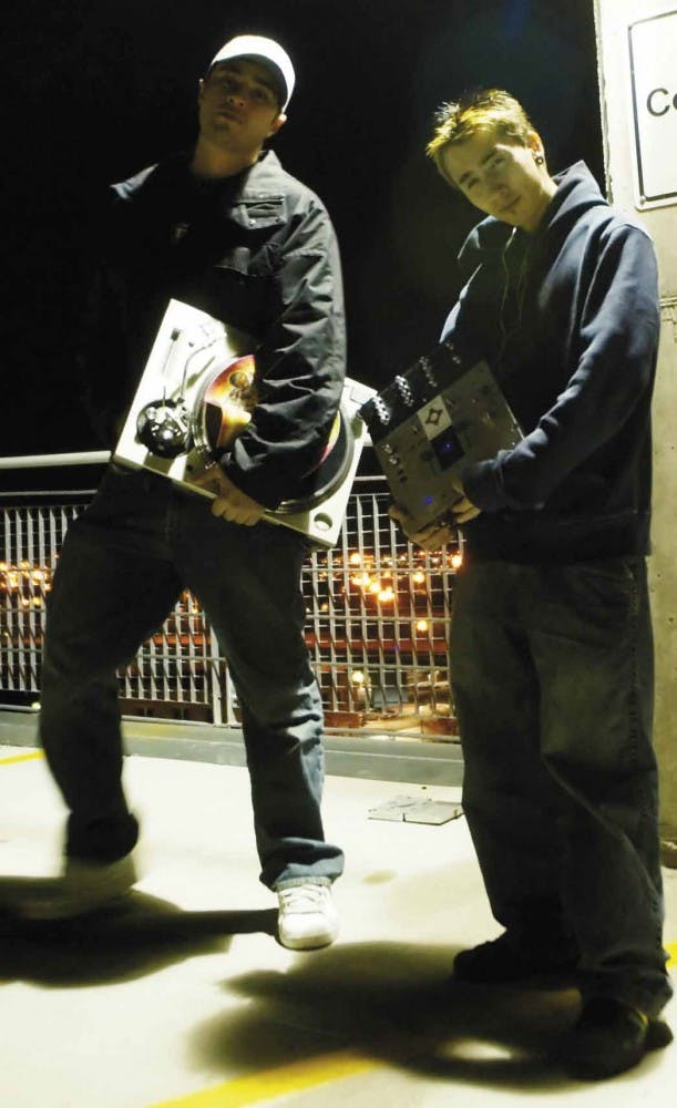 Turntablists Ohm, left, and Kiddo of Five Oh Fresh stand in the Downtown Parking Structure holding a mixer and turntable Monday. The duo will perform March 15 at the Launchpad at 618 Central Ave. S.W.