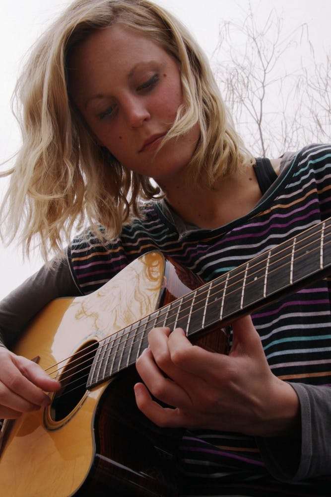 	Meredith Wilder plays guitar outside Zimmerman Library on Monday. She plays folk music at
open mic nights and local venues.